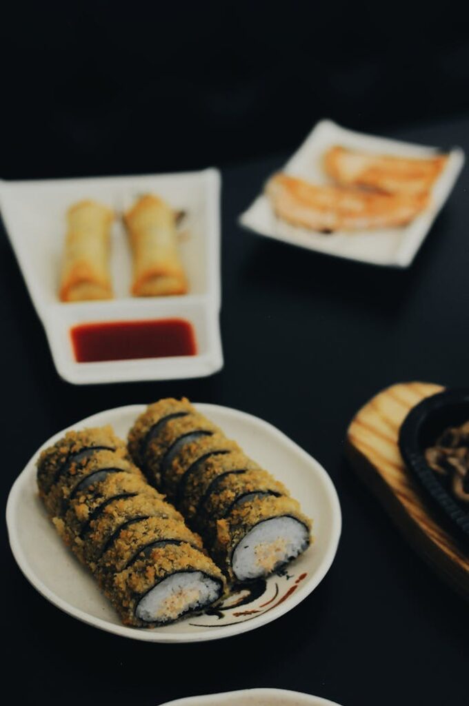 A mouthwatering spread of fried sushi, spring rolls, and gyoza in an indoor dining setting.