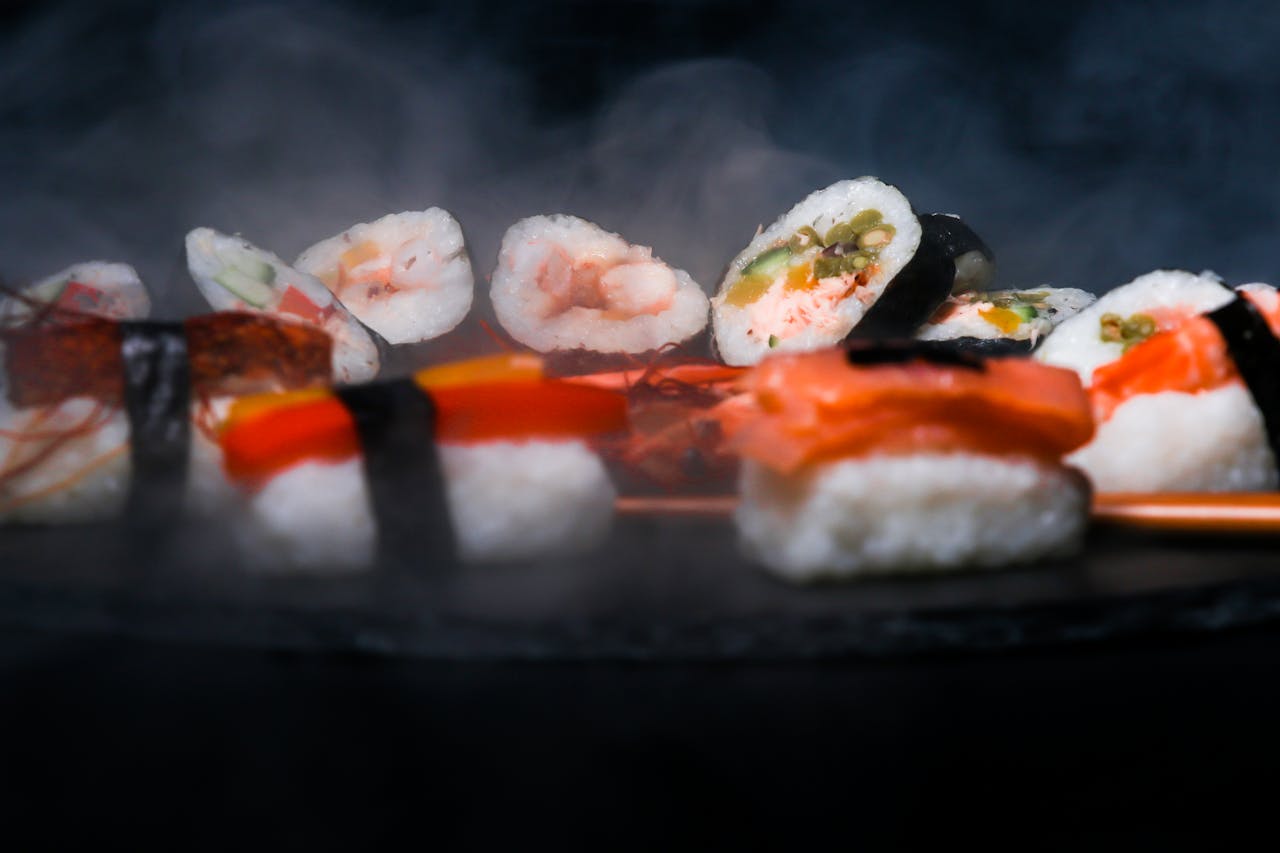 Close-up of assorted sushi rolls with steam, showcasing traditional Japanese cuisine.